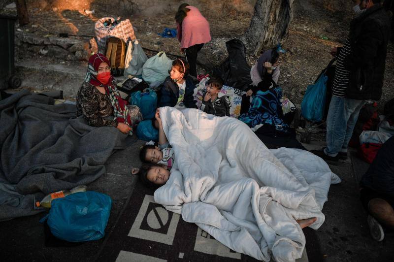 Miles de personas pasan la noche a la intemperie en los alrededores del devastado campo de refugiados de Moria (Lesbos), el más grande de Grecia, a la espera de ser trasladados. Las carreteras que rodean el campo, en el que malvivían 13.000 personas, están repletas de familias que con lo poco que les ha quedado se han instalado en la calzada o en alguna cercana al campo que no ha sido destruida por el incendio del martes por la noche; un incendio que comenzó simultáneamente en varios puntos del campo, poco después de que las autoridades comunicaran a 35 personas que habían dado positivo de covid-19 y que debían ser aisladas. 