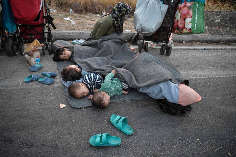 Miles de personas pasan la noche a la intemperie en los alrededores del devastado campo de refugiados de Moria (Lesbos), el más grande de Grecia, a la espera de ser trasladados. Las carreteras que rodean el campo, en el que malvivían 13.000 personas, están repletas de familias que con lo poco que les ha quedado se han instalado en la calzada o en alguna cercana al campo que no ha sido destruida por el incendio del martes por la noche; un incendio que comenzó simultáneamente en varios puntos del campo, poco después de que las autoridades comunicaran a 35 personas que habían dado positivo de covid-19 y que debían ser aisladas. 