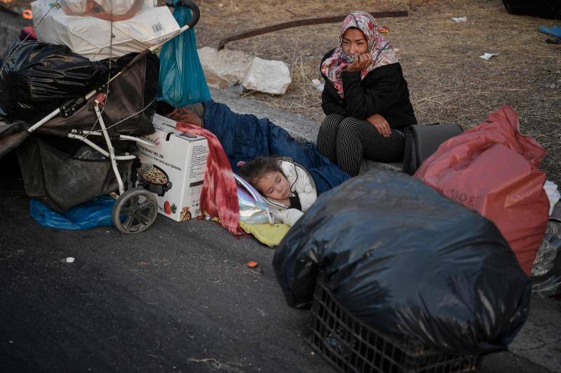 Miles de personas pasan la noche a la intemperie en los alrededores del devastado campo de refugiados de Moria (Lesbos), el más grande de Grecia, a la espera de ser trasladados. Las carreteras que rodean el campo, en el que malvivían 13.000 personas, están repletas de familias que con lo poco que les ha quedado se han instalado en la calzada o en alguna cercana al campo que no ha sido destruida por el incendio del martes por la noche; un incendio que comenzó simultáneamente en varios puntos del campo, poco después de que las autoridades comunicaran a 35 personas que habían dado positivo de covid-19 y que debían ser aisladas. 