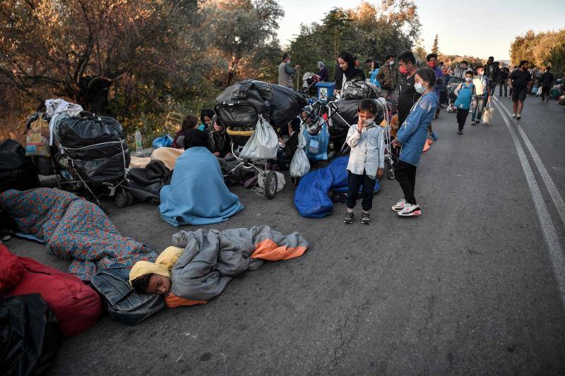 Miles de personas pasan la noche a la intemperie en los alrededores del devastado campo de refugiados de Moria (Lesbos), el más grande de Grecia, a la espera de ser trasladados. Las carreteras que rodean el campo, en el que malvivían 13.000 personas, están repletas de familias que con lo poco que les ha quedado se han instalado en la calzada o en alguna cercana al campo que no ha sido destruida por el incendio del martes por la noche; un incendio que comenzó simultáneamente en varios puntos del campo, poco después de que las autoridades comunicaran a 35 personas que habían dado positivo de covid-19 y que debían ser aisladas. 