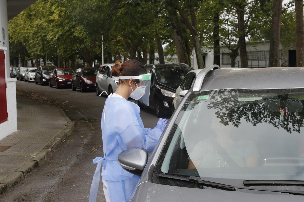Una sanitaria del puesto de autocovid instalado en el complejo deportivo de Las Mestas realiza una PCR a una profesora. 
