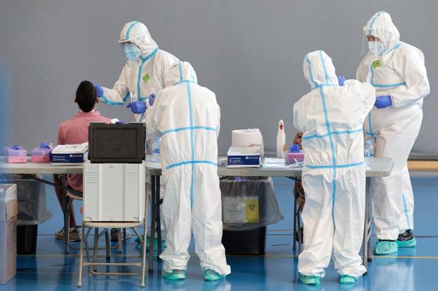 Personal sanitario realiza PCR durante un cribado masivo en Gerona. En el vídeo, últimos avances sobre la vacuna.