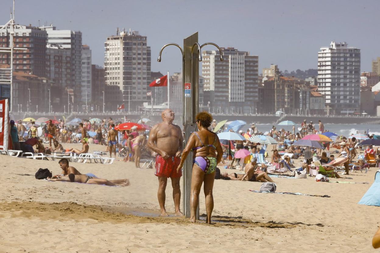 Un hombre y una mujer se refrescan en las duchas de San Lorenzo. 