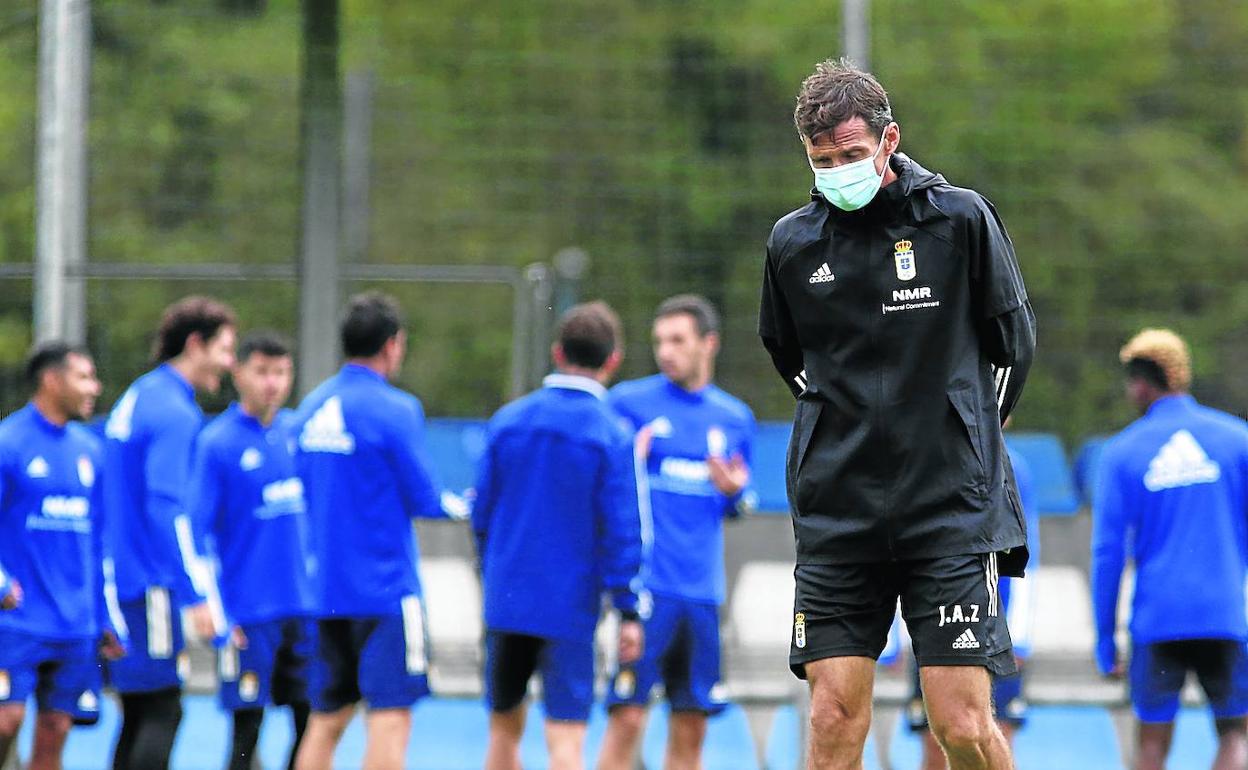 El entrenador José Ángel Ziganda, pensativo, sobre el césped de El Requexón, con sus jugadores al fondo.