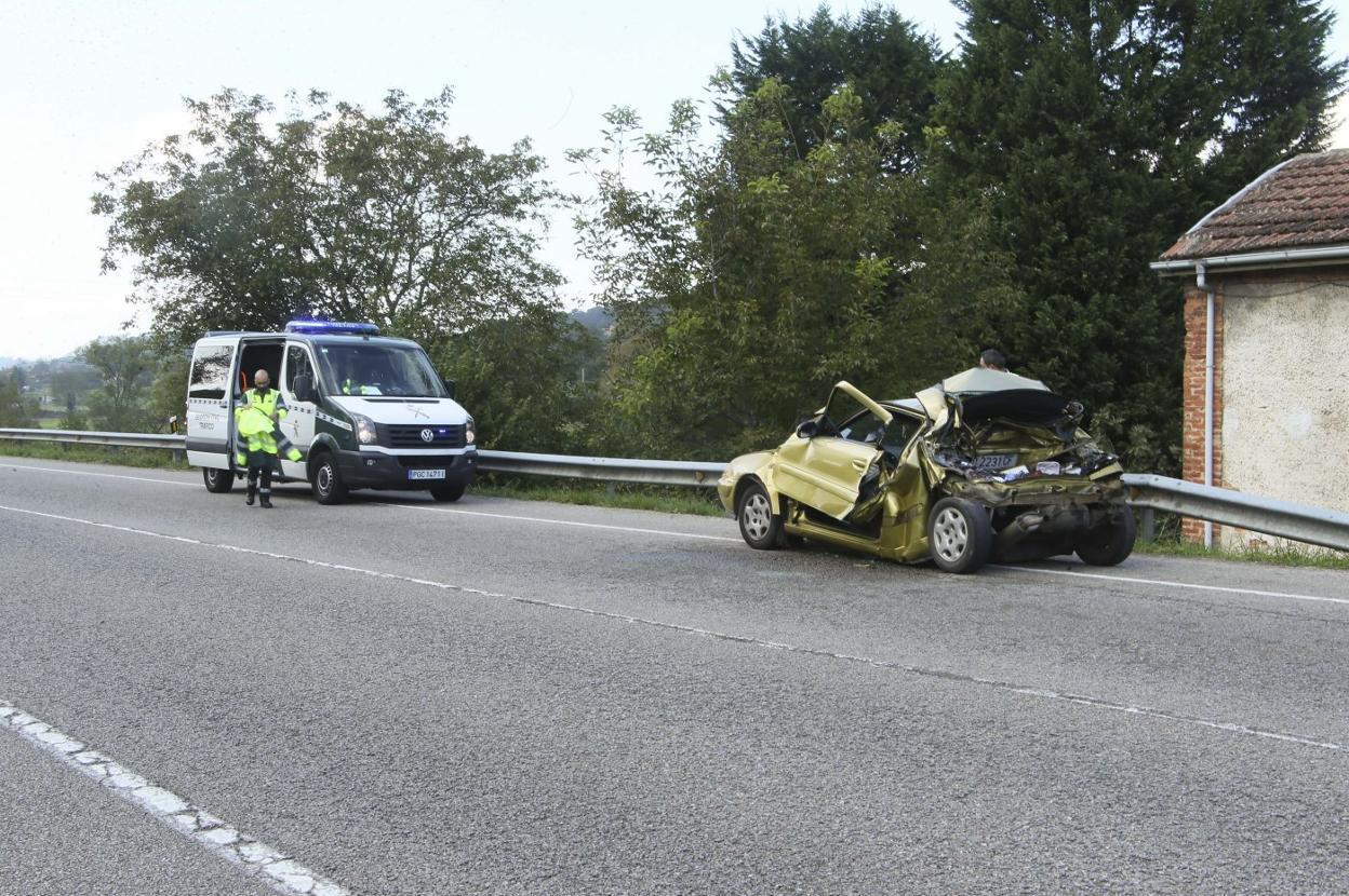 Un furgón de la Guardia Civil junto al coche destrozado en la colisión. 