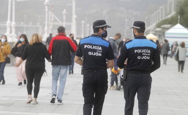 Dos agentes de Policía Local de Gijón patrullan por el Muro.