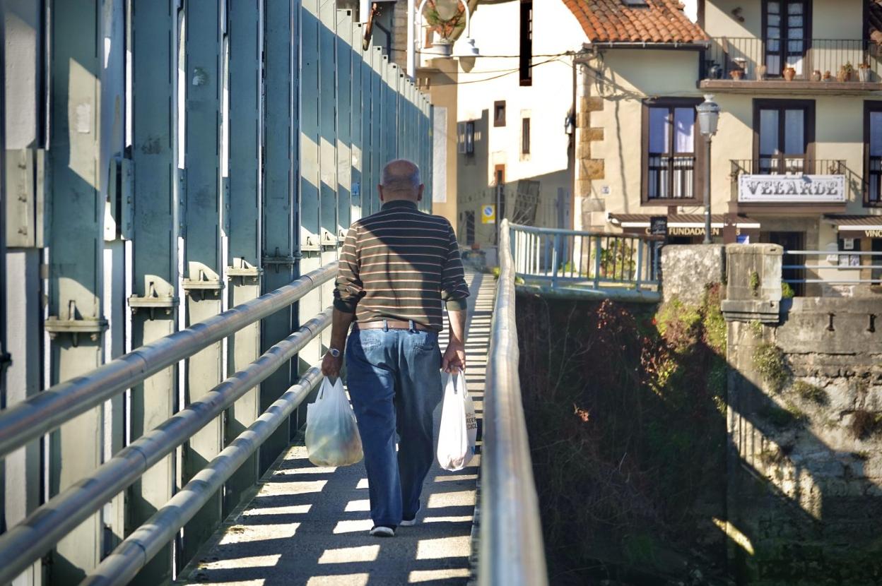 Un vecino de Bustio cruza el puente, con la compra recién hecha en Unquera, entre Cantabria y Asturias. 