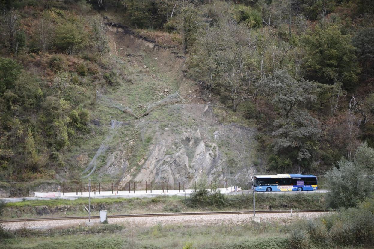 Un autobús circula por la carretera junto al tramo afectado por el argayo. 