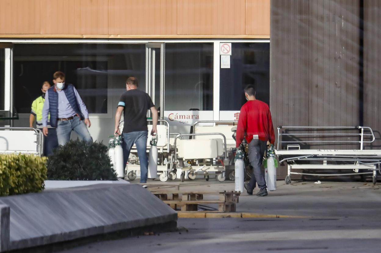 Dos personas llevan material sanitario al hospital de campaña del recinto ferial gijonés. 