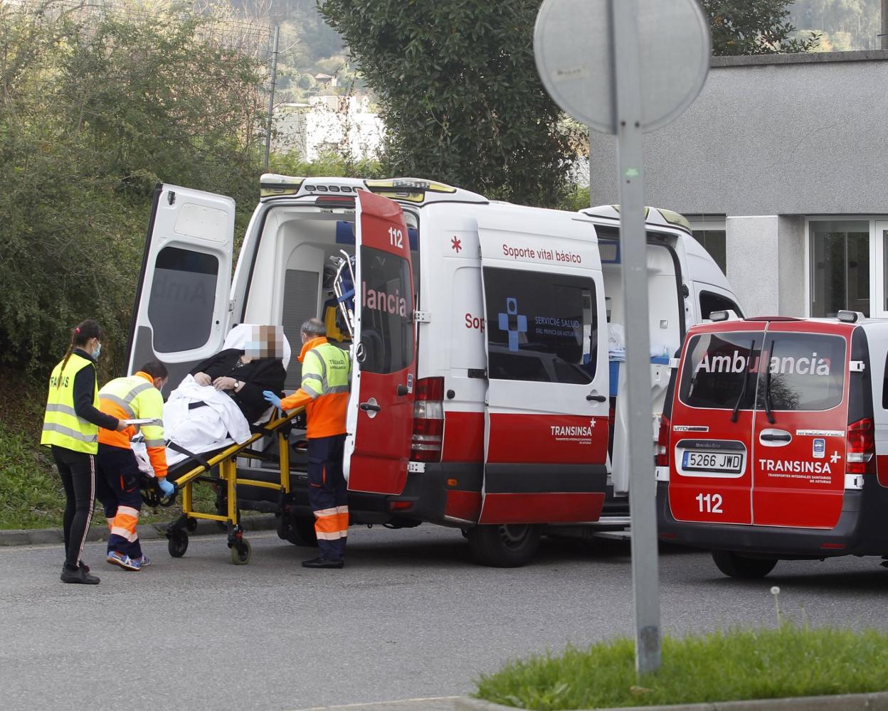 Varios sanitarios bajan de una ambulancia a una persona mayor, en la zona de acceso a las Urgencias del Hospital de Cabueñes. 