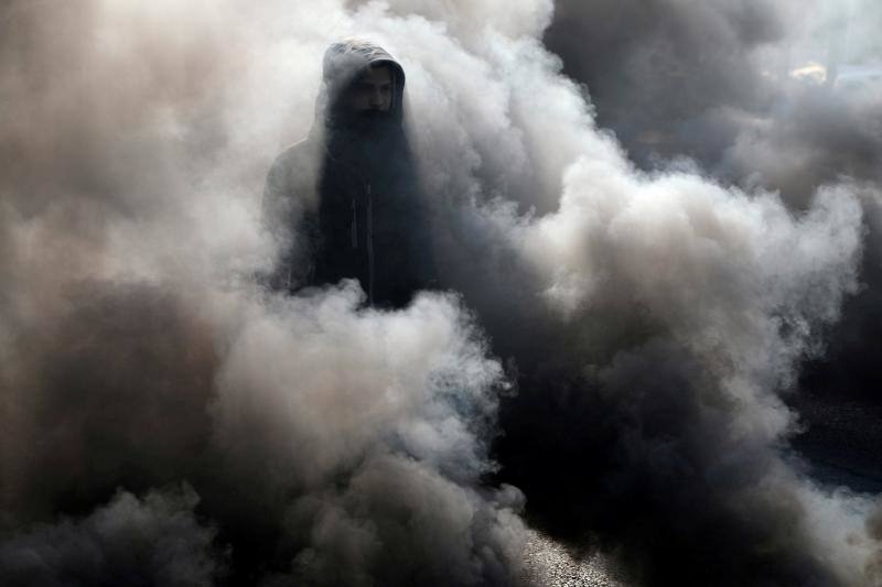 Un manifestante iraquí camina entre el humo de la quema de neumáticos durante las protestas antigubernamentales en curso en Kerbala, Irak, el 20 de enero de 2020. 