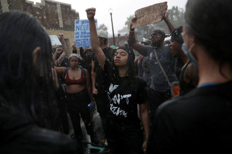 La lluvia cae mientras Monie Scott levanta el puño al tiempo que la gente canta a su alrededor durante un evento en recuerdo a George Floyd, en Minneapolis, Minnesota, EE UU, 2 de junio de 2020. 