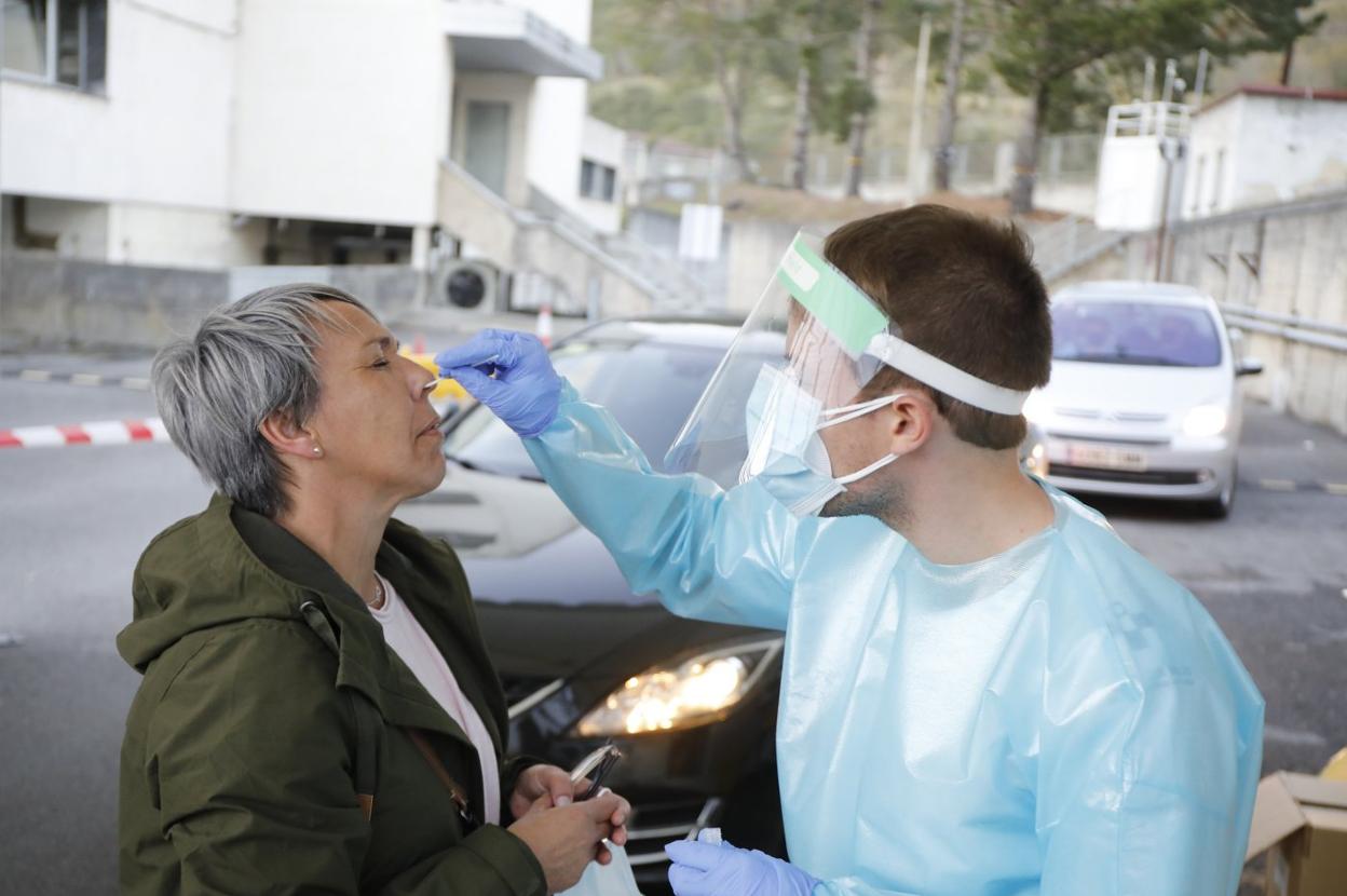 Un sanitario recoge una muestra en la nariz de una vecina de Langreo, en el 'auto-covid', para posteriormente enviarla al laboratorio. 