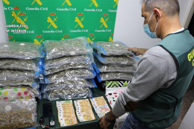 Un agente con parte del material intervenido, bolsas de cannabis, dinero en efectivo y teléfonos. 