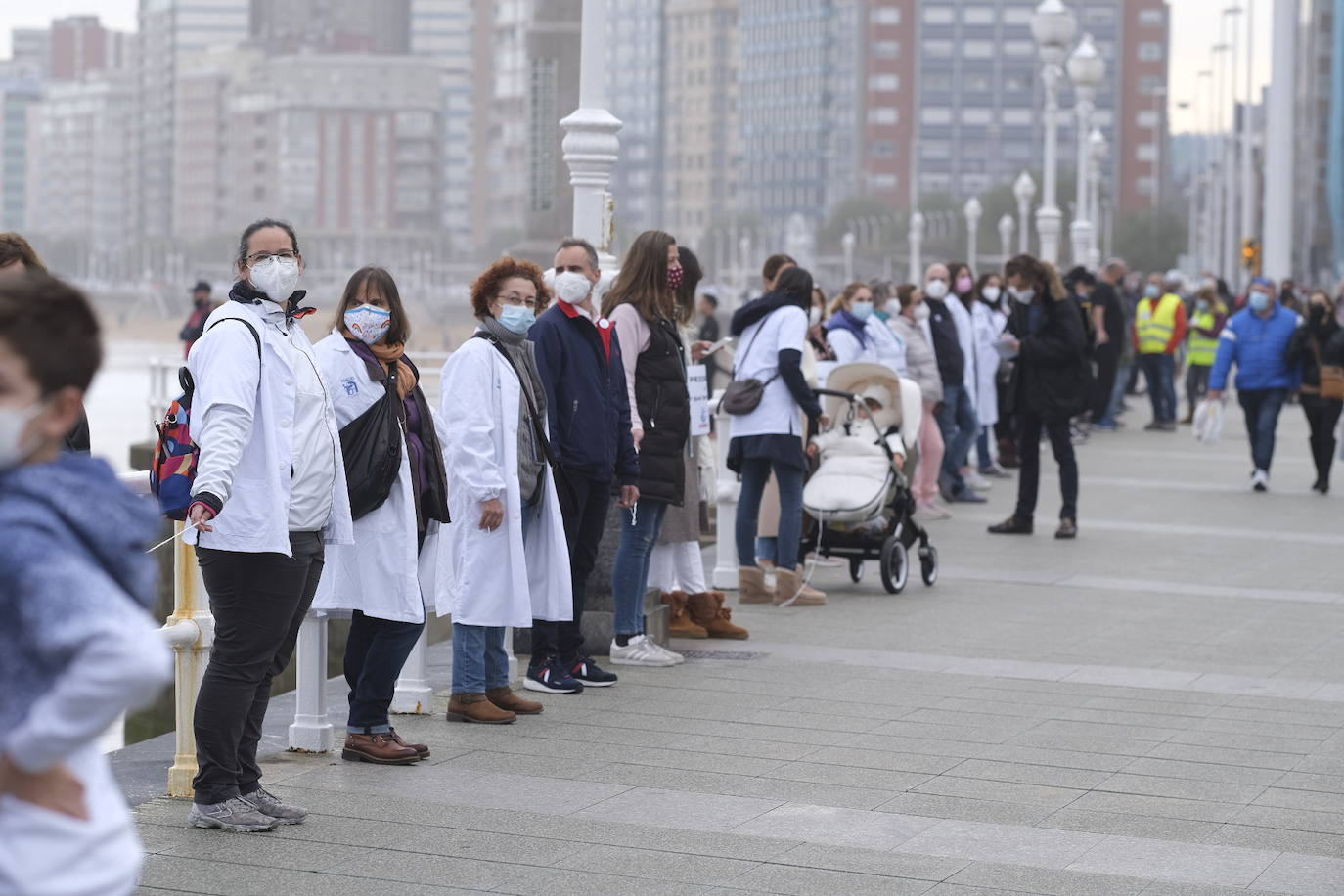 Decenas de personas se han sumado a una cadena humana en el muro de San Lorenzo, en Gijón. Se trata de una iniciativa en defensa de la sanidad pública.