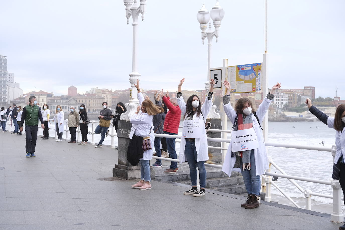 Decenas de personas se han sumado a una cadena humana en el muro de San Lorenzo, en Gijón. Se trata de una iniciativa en defensa de la sanidad pública.