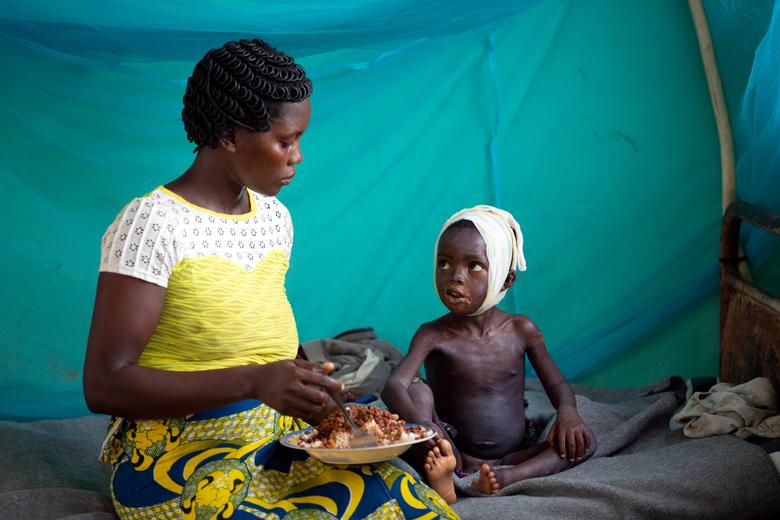 Congo | Allay Ngandema, de tres años, quien ha desarrollado complicaciones después de contraer sarampión, almuerza con su madre Maboa Alpha en la sala de aislamiento de sarampión en el hospital Boso-Manzi en la provincia de Mongala en el norte de la República Democrática del Congo