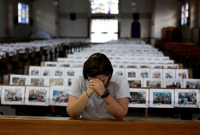 Costa Rica | La católica Adriana Brenes ora durante una misa transmitida en vivo mientras las fotos de los fieles se muestran sobre los bancos de la iglesia en la iglesia de Nuestra Señora de Fátima, mientras continúa la propagación del coronavirus en San José