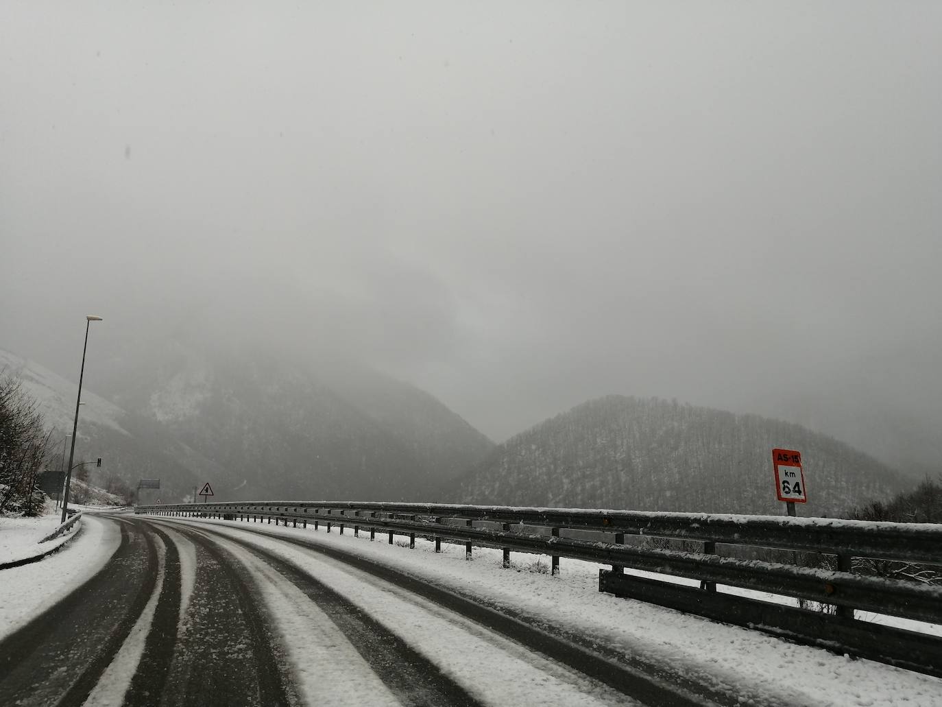 La borrasca 'Bella' ha provocado más de 1.900 incidencias en Asturias y complica las comunicaciones. La nieve acumulada en las últimas horas, que ha cerrado el puerto del Connio, obliga a usar cadenas en 15 altos de montaña. Los fuertes vientos han procovado la caída de árboles y la Aemet mantiene el litoral del Principado en alerta roja por olas de hasta diez metros 