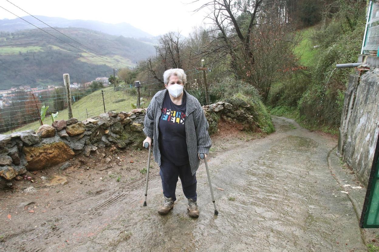 Emi Rodríguez, vecina de Villarín, en Oviedo, con la pista de acceso al pueblo tras ella. 