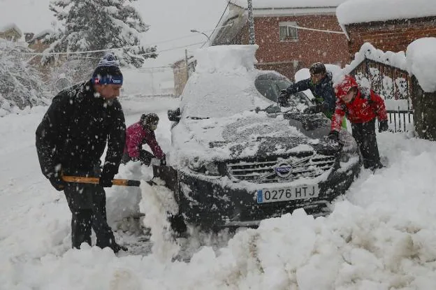 Una familia, en plena faena para liberar su automóvil de la nieve, en la localidad allerana de Felechosa. 