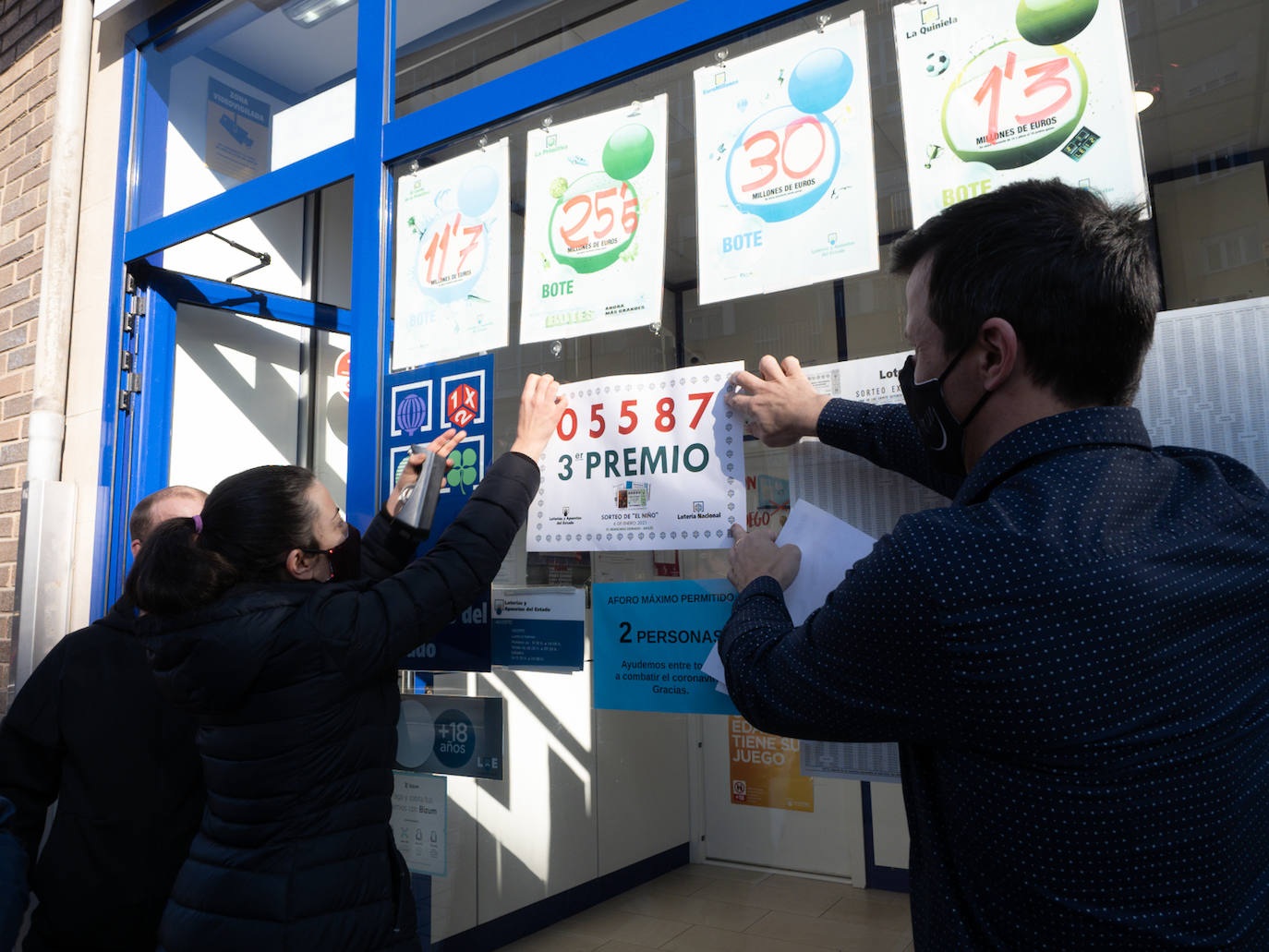 Los propietarios de la administración avilesina cuelgan un cartel con el número premiado 