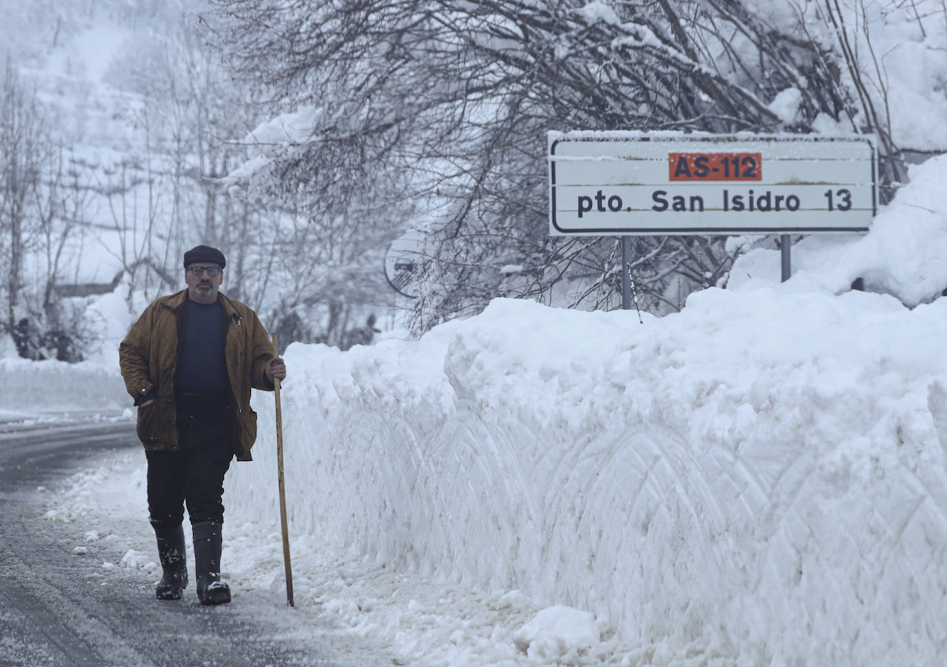 Imagen principal - En el puerto de San Isidro se han acumulado varios metros de nieve. Juan Rico, Al izquierda, Manuel Díaz, José Cangas y Avelino Alonso, en el puerto de San Isidro. A la derecha, un coche entre la impresionante nevada camino de Tielve.