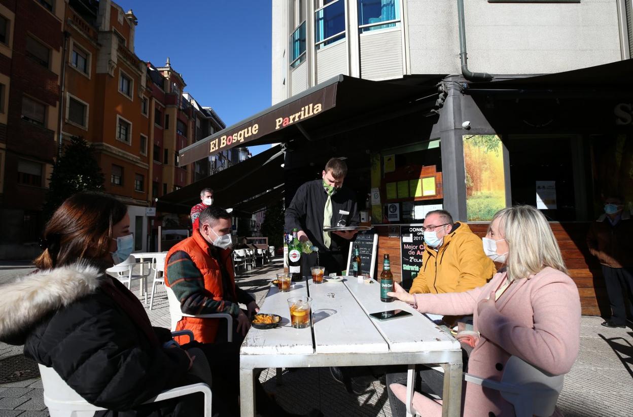 Una familia disfruta del aperitivo y del buen tiempo en la terraza de la sidrería El Bosque. 