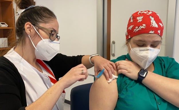 Una sanitaria vacuna a una compañera.