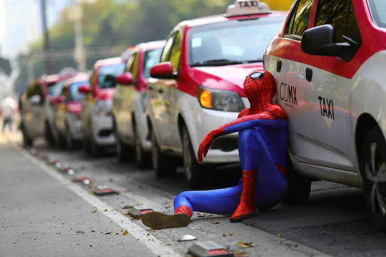 Una persona vestida como Spider-Man se sienta junto a los taxis mientras los taxistas realizan una protesta contra las aplicaciones de taxis como Uber, Cabify y Didi en el monumento Ángel de la Independencia, en la Ciudad de México.
