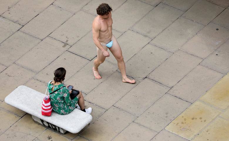 Un hombre que lleva una máscara quirúrgica como tanga pasa junto a una mujer en Oxford Street en Londres.