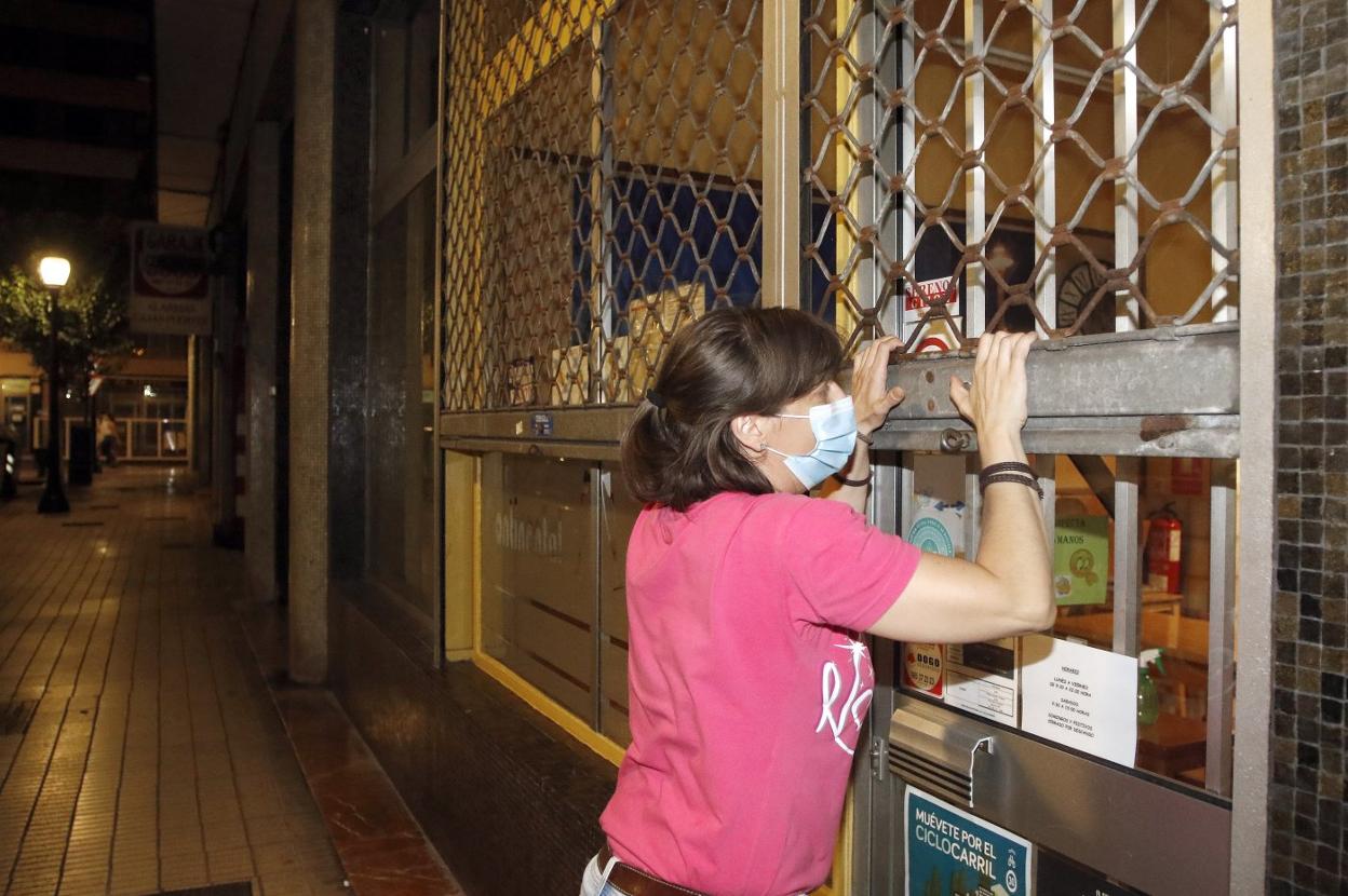 La responsable de un bar baja la persiana del establecimiento. 