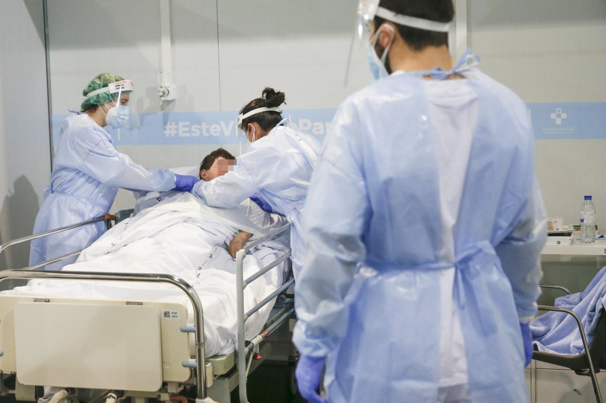 Tres profesionales sanitarios dan atención a una paciente ingresada en el H144, el hospital para casos covid habilitado en el recinto ferial gijonés Luis Adaro. 