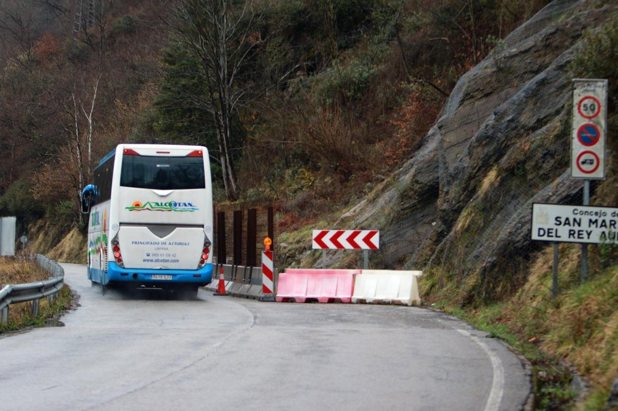 Un autobús circula junto al tramo de la carretera de Blimea afectado por un argayo. 