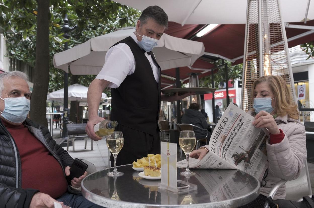 Dos gijoneses disfrutan de una terraza en la calle Corrida. 
