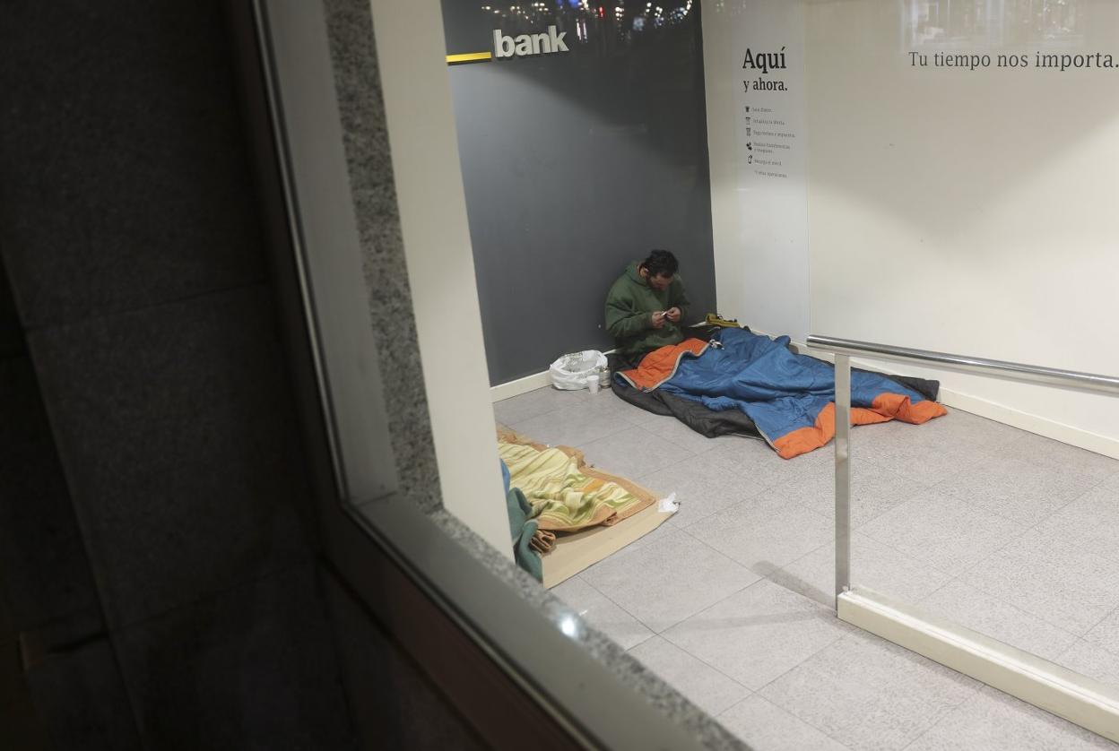 Una persona sin hogar duerme en un cajero de Gijón. 