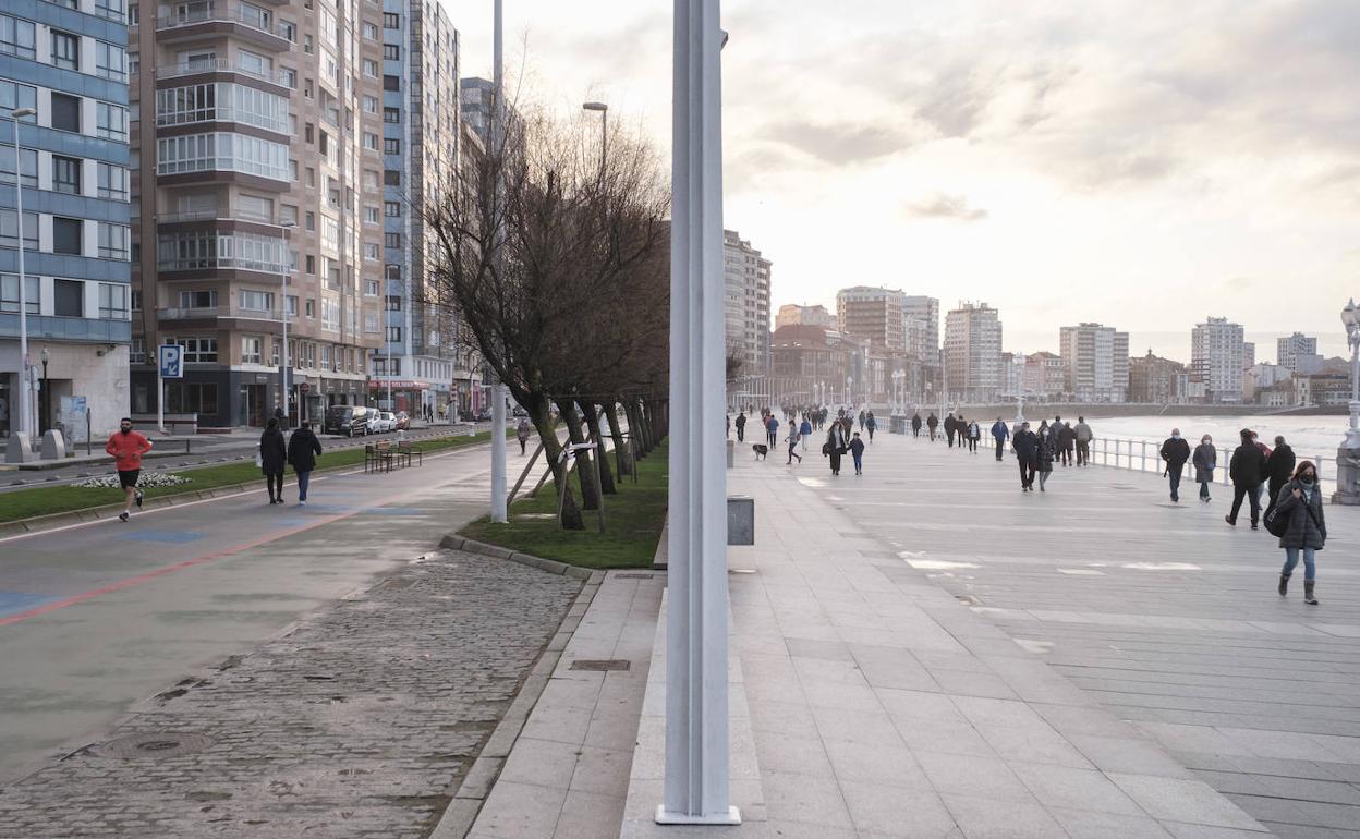 Varias personas, de paseo por Gijón en un día nuboso 