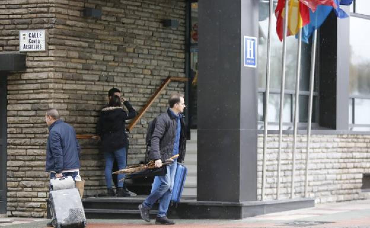 Un tarista sale de un hotel de Gijón. 