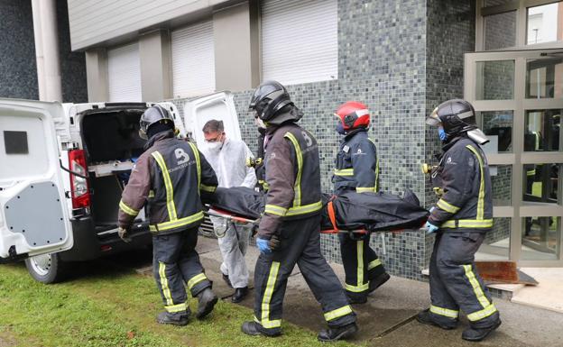 Efectivos de Bomberos sacan uno de los dos cuerpos del bloque de viviendas de Villaviciosa afectado por un incendio.