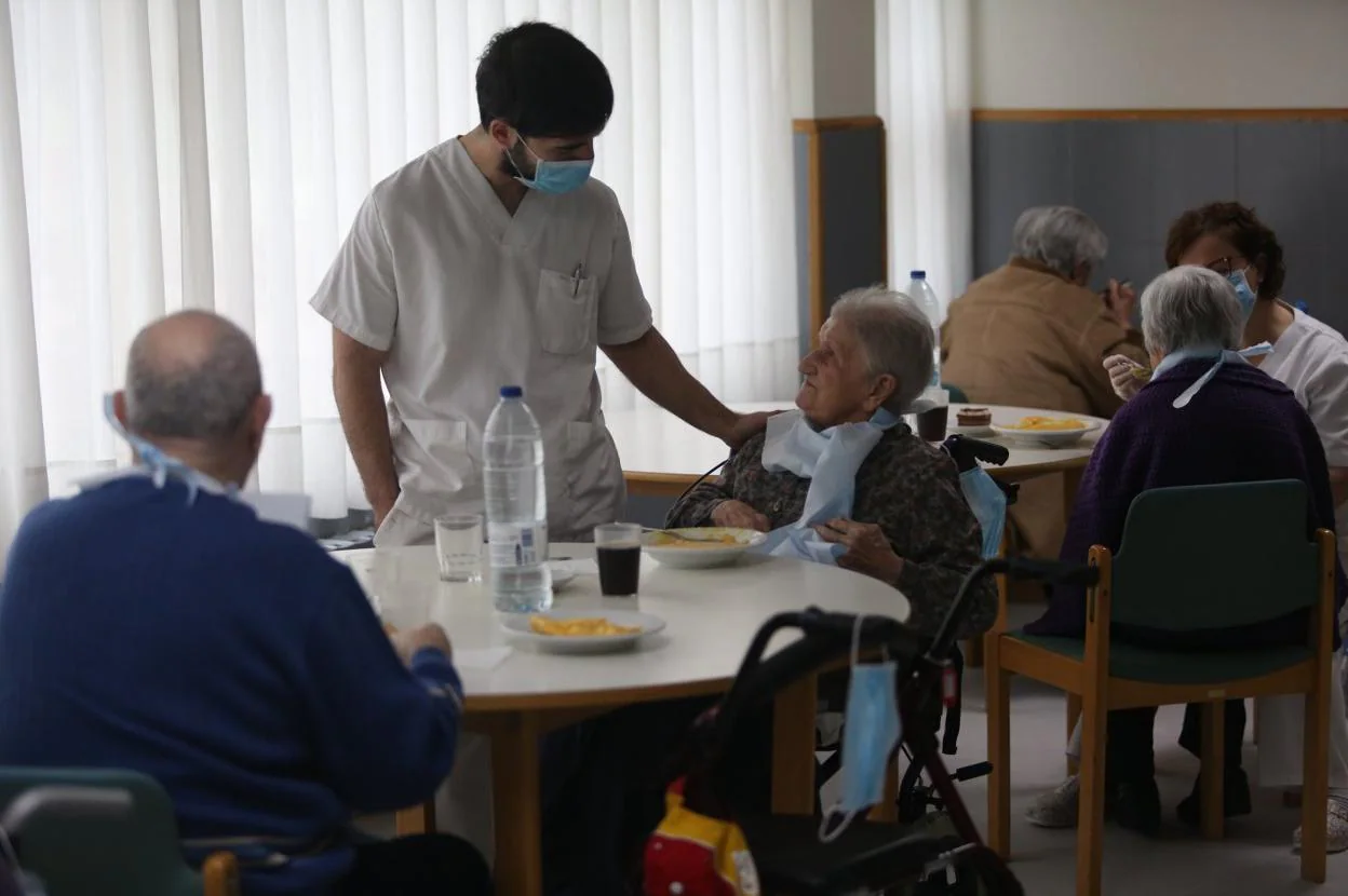 Un cuidador departe con una de las usuarias de la residencia geriátrica de Grado durante el turno de comidas. 