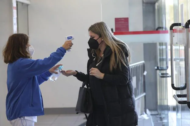 Una sanitaria toma la temperatura a una docente a la entrada del Palacio de Deportes de Gijón. 