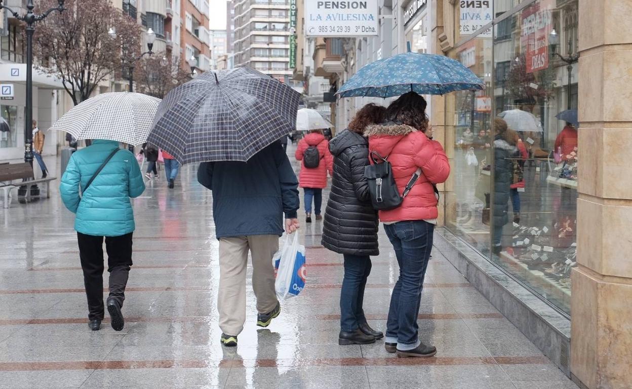 Paseantes por el centro de Gijón en una jornada de lluvia. 