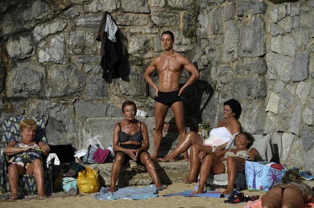 Un grupo de personas tomando el sol en el Tostaderu, en la playa San Lorenzo.