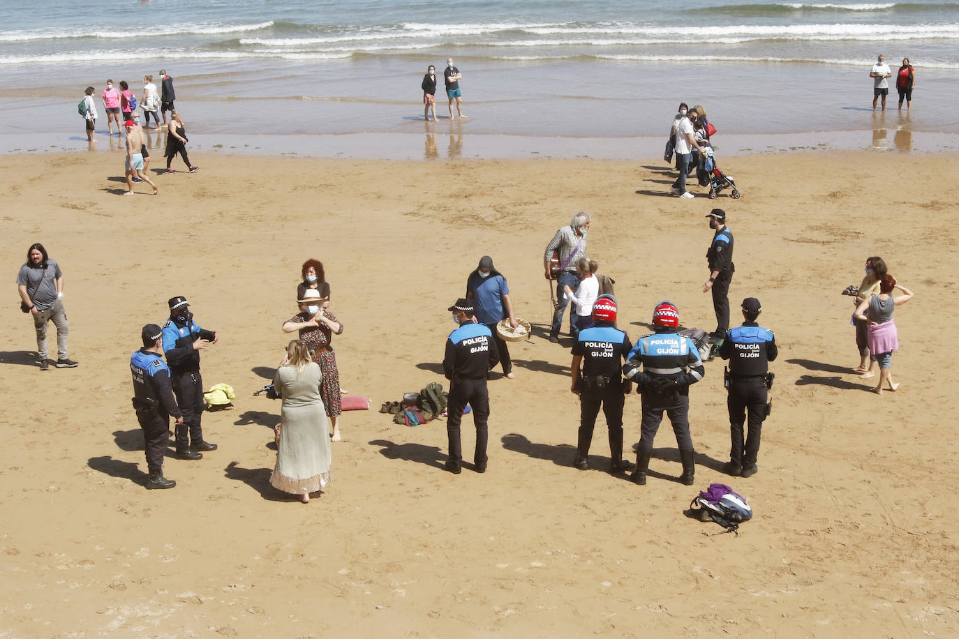 Amplio dispositivo policial en la mañana de este sábado en la playa de San Lorenzo para disolver a un grupo de personas que permanecía en el arenal sin mascarilla. Fueron obligados por los agentes a ponerse las protecciones.