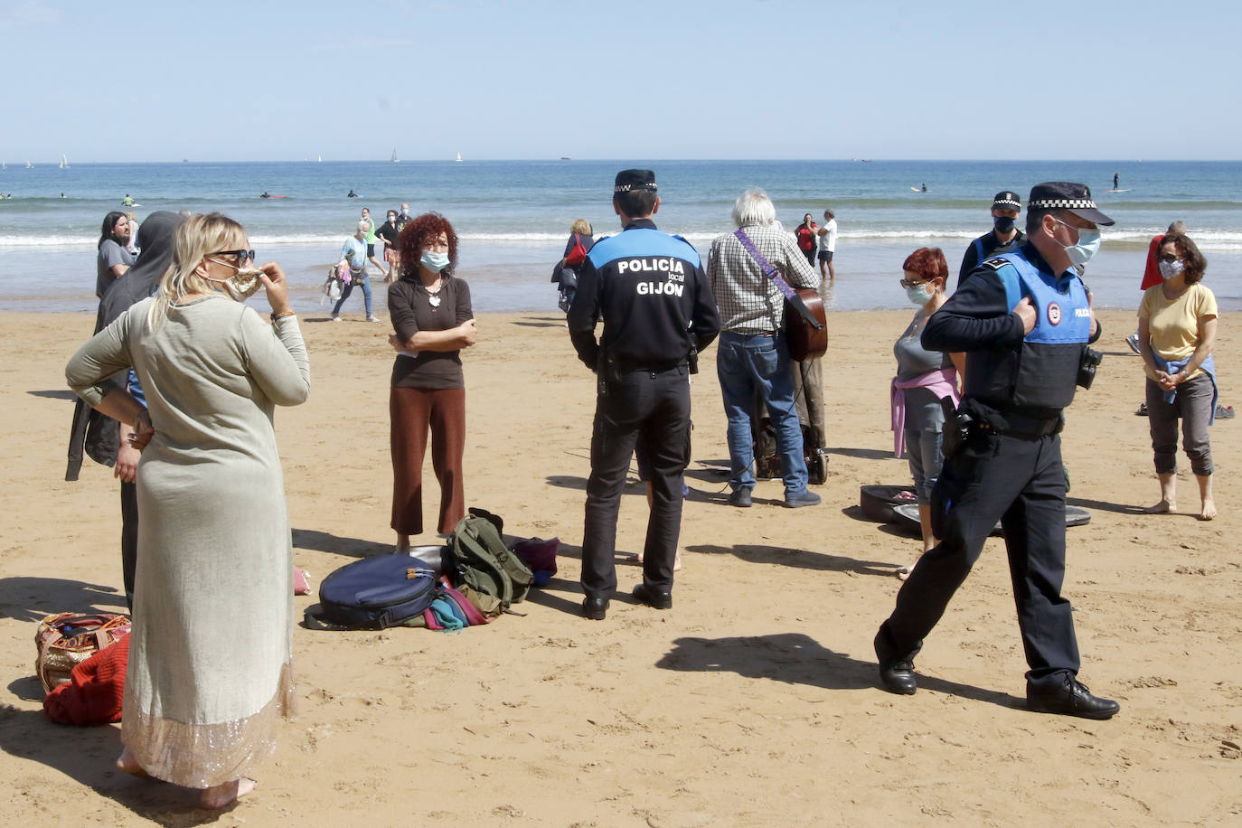 Amplio dispositivo policial en la mañana de este sábado en la playa de San Lorenzo para disolver a un grupo de personas que permanecía en el arenal sin mascarilla. Fueron obligados por los agentes a ponerse las protecciones.