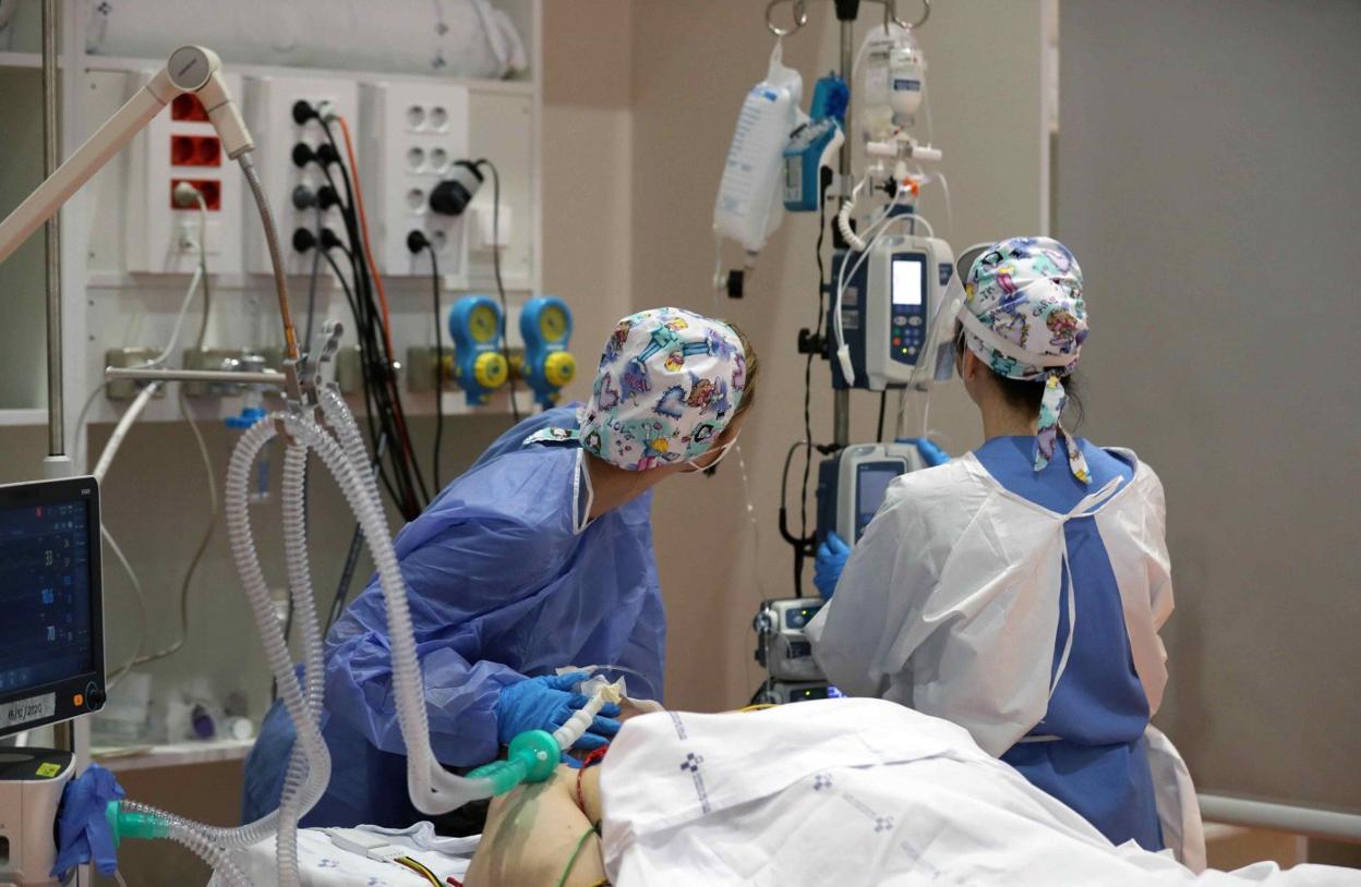 Dos profesionales sanitarias atienden a uno de los pacientes críticos ingresados en la UCI del HUCA. 