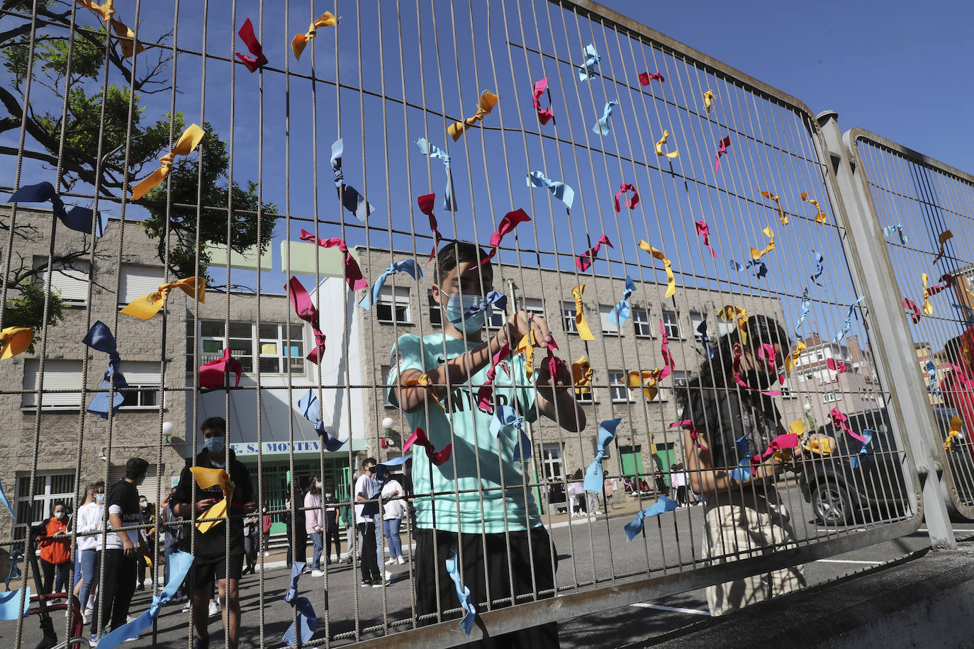 Un total de 150 alumnos han salido de sus clases para realizar un acto en el que los escolares han colocado lazos de colores, que contienen deseos formulados con la ilusión de un viaje, en la valla frontal del patio para formar una cadena de deseos entrelazados.