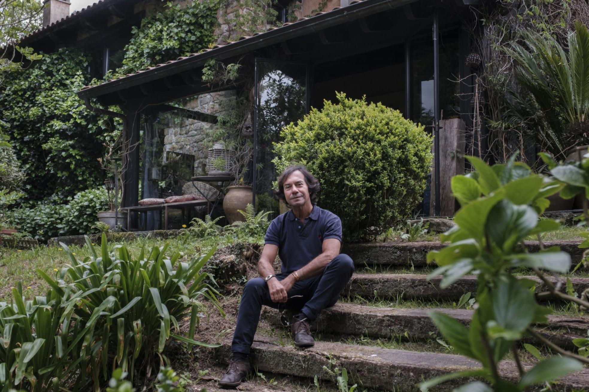 El interiorista Antonio Martínez en las escaleras de acceso a su casa, ubicada en un bonito valle del concejo de Villaviciosa. 