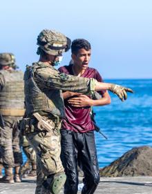 Imagen secundaria 2 - Brahim, en el centro, a su llegada a la playa del Tarajal (arriba), varios inmigrantes asistidos por el Ejército y Cruz Roja.