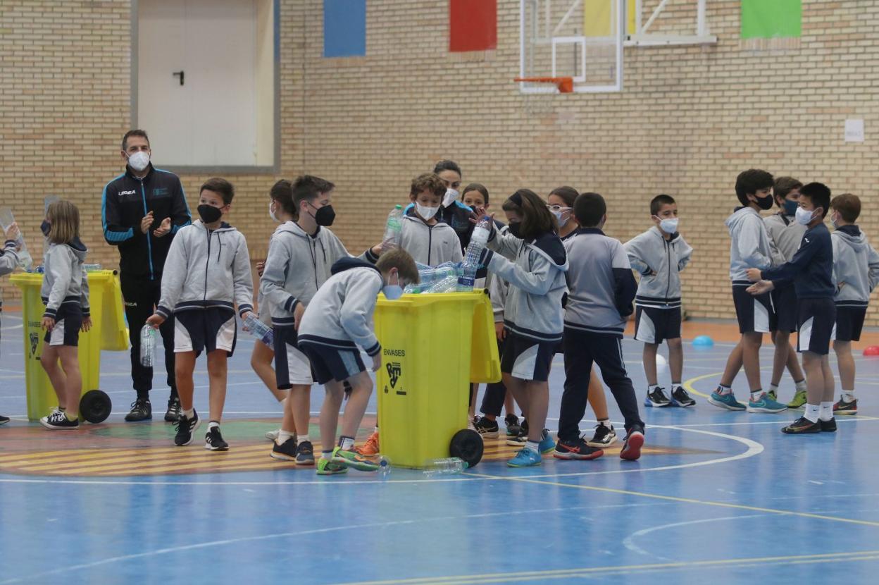 Alumnos del Palacio de Granda tiran en los contenedores las botellas recogidas en la carrera. 